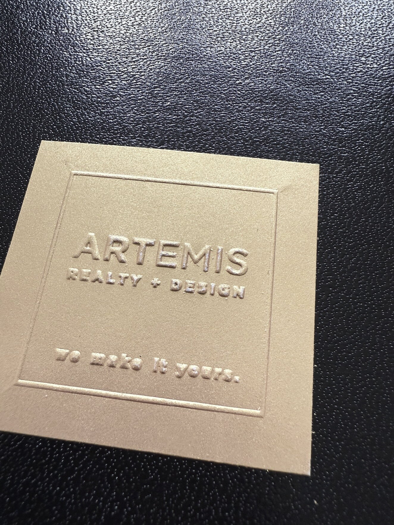 A leather folder embossed with the Artemis Realty and Design mark